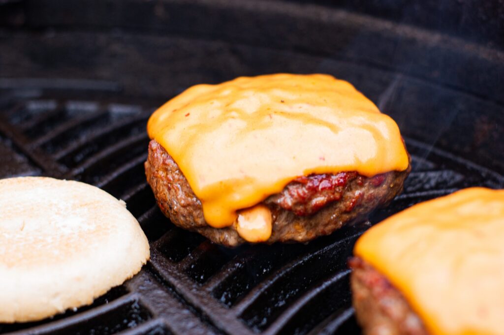 Hamburger op de kamado: cheeseburger met gesmolten cheddar op het gietijzeren rooster