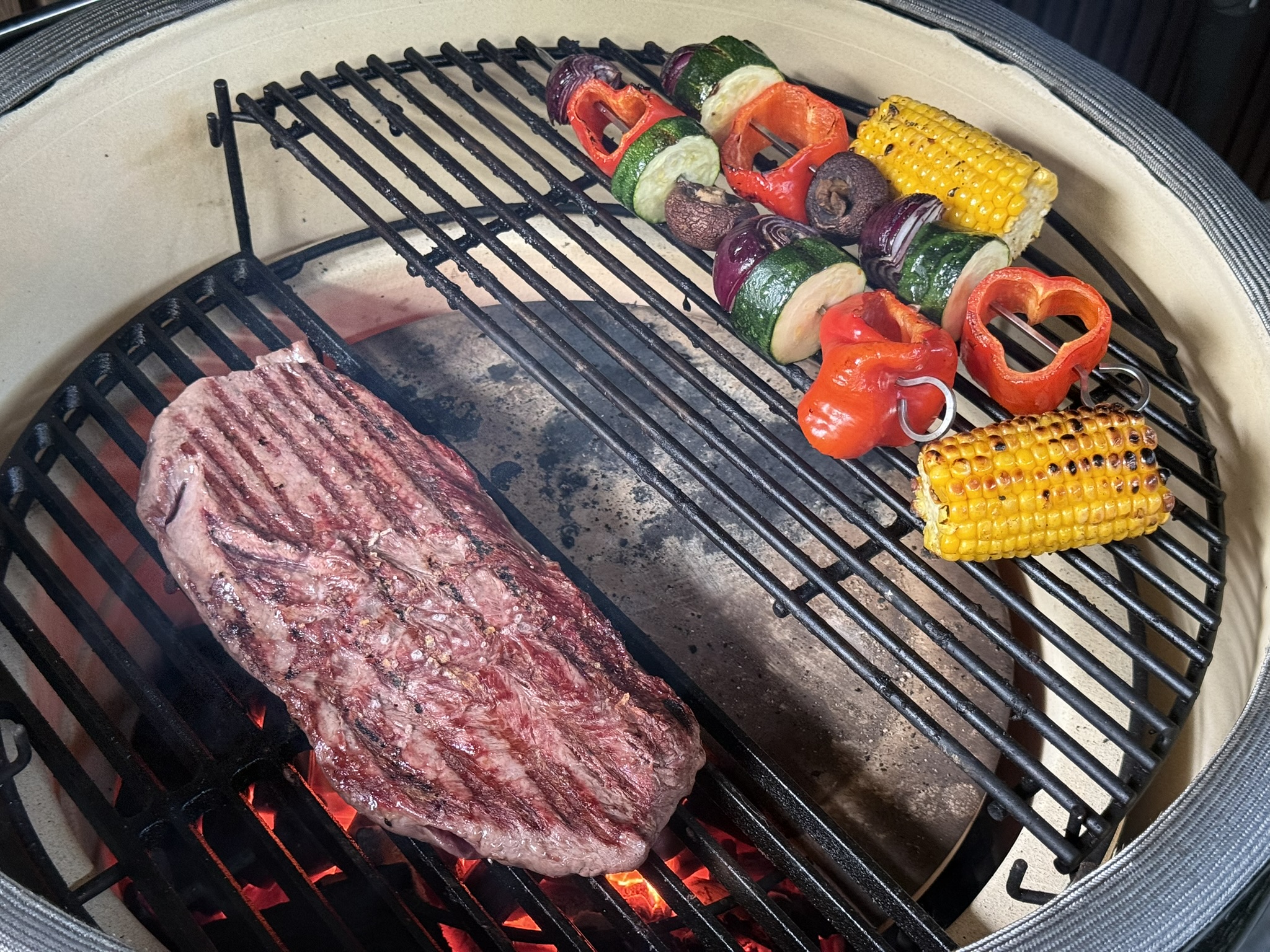 Flat iron steak direct boven de kolen naast een indirecte zone met groentespiesjes op een kamado