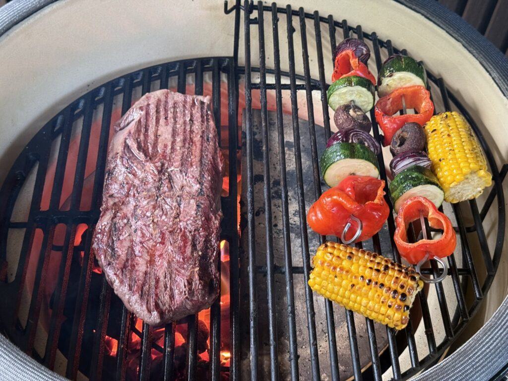 Flat iron steak met diamantruit van grillstrepen op het gietijzeren rooster van de kamado