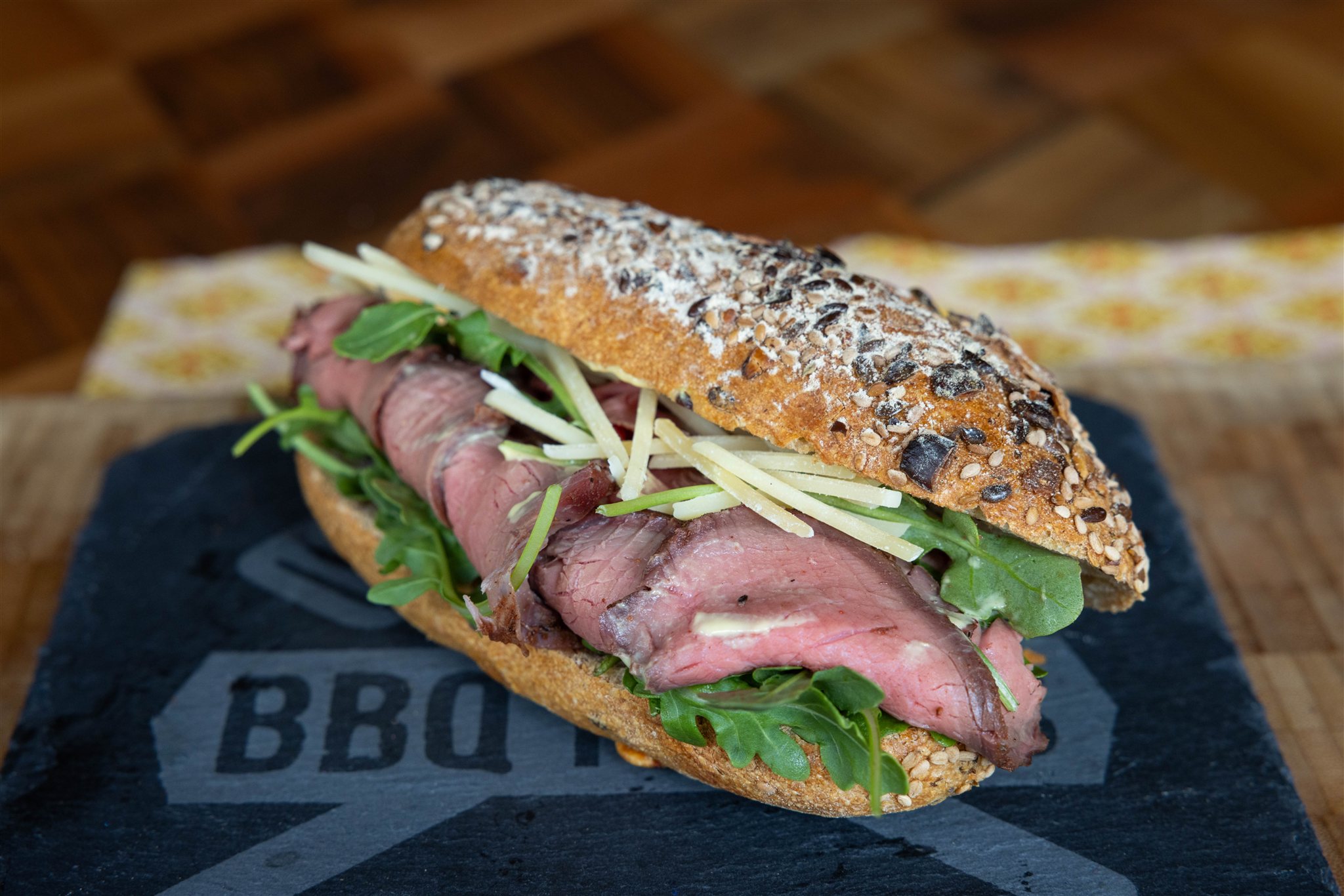 Broodje rosbief van de bbq met rucola en oude kaas op een leisteen serveerplank