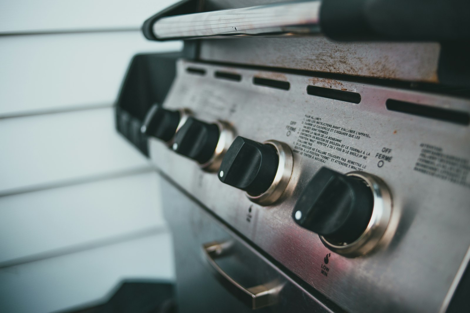 Close-up van de draaiknoppen van een gasbarbecue met rvs-bedieningspaneel